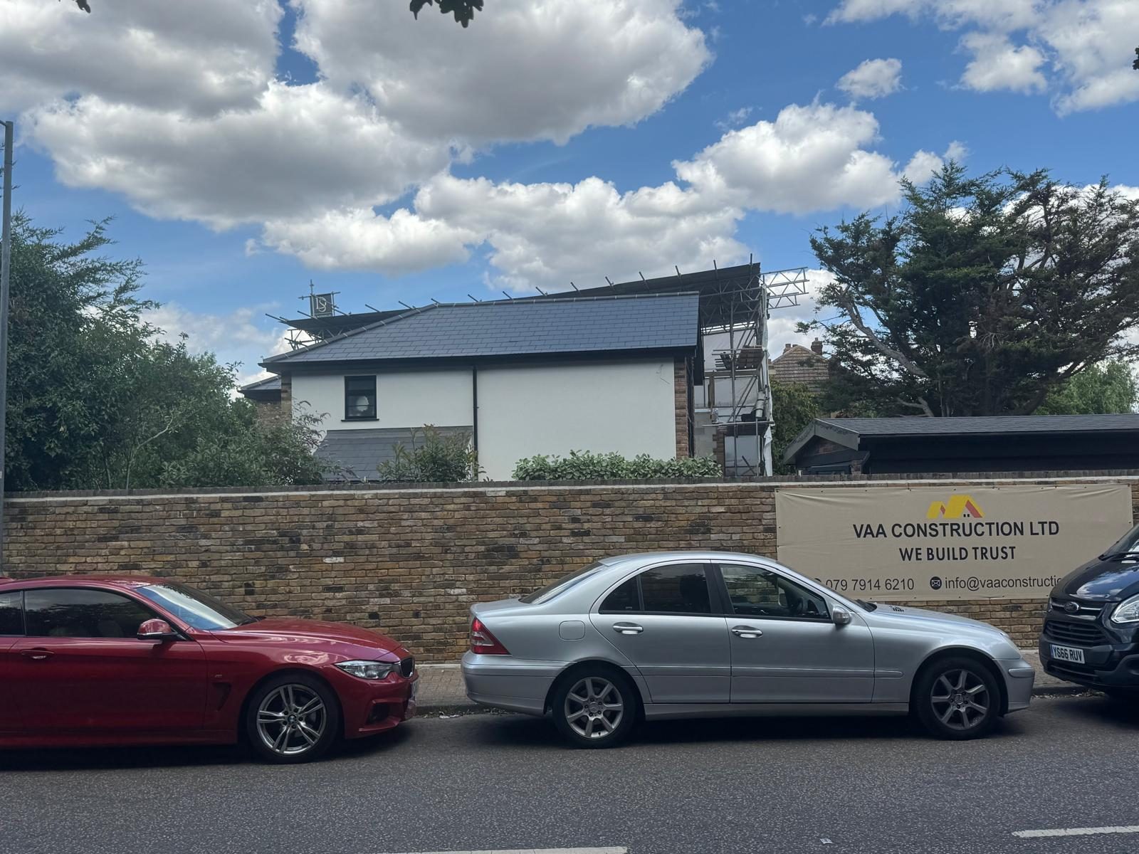 Finished rendered house behind a new brick boundary wall with a VAA Construction site board