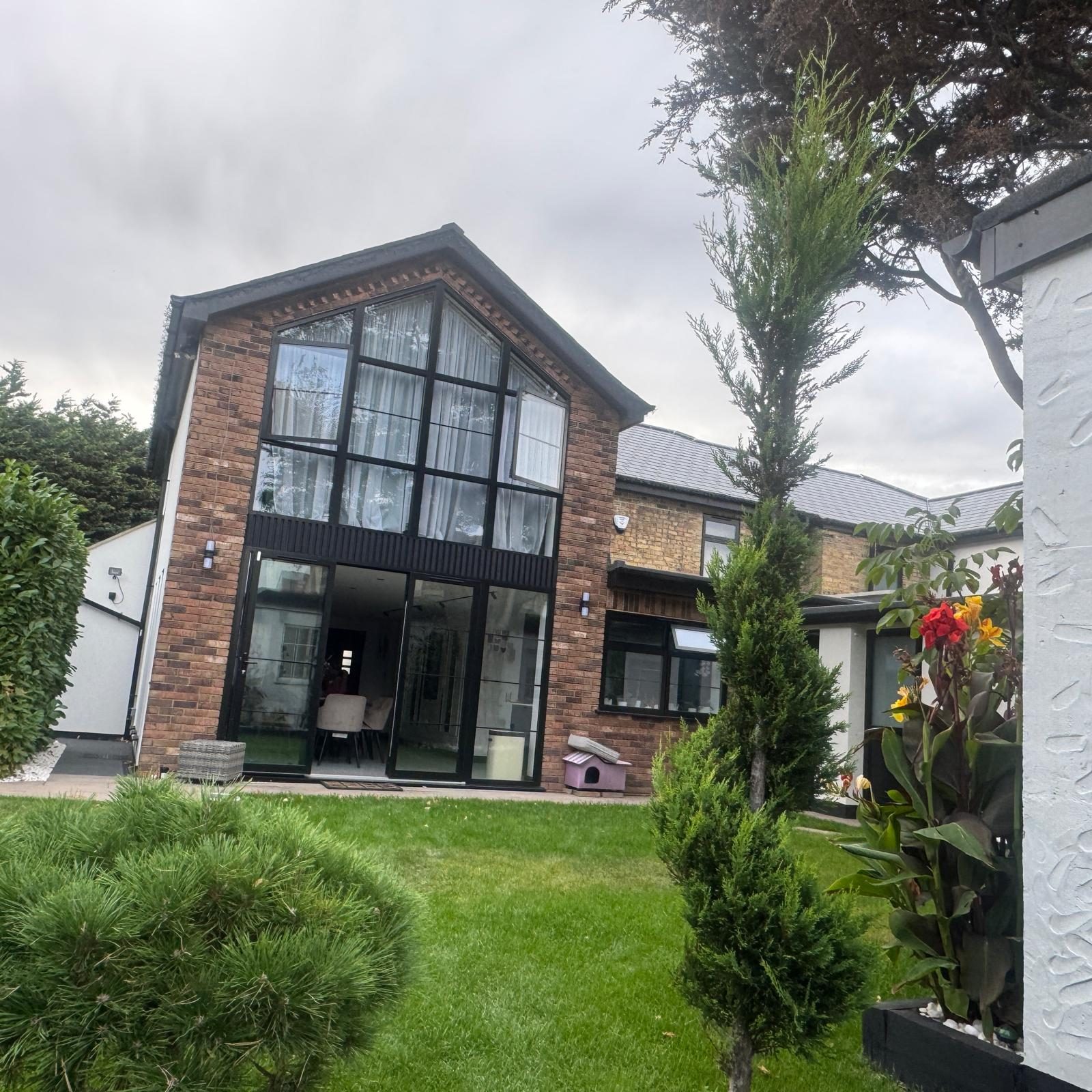Full-height glazed gable end on a brick extension with planting in front, built by VAA Construction Ltd