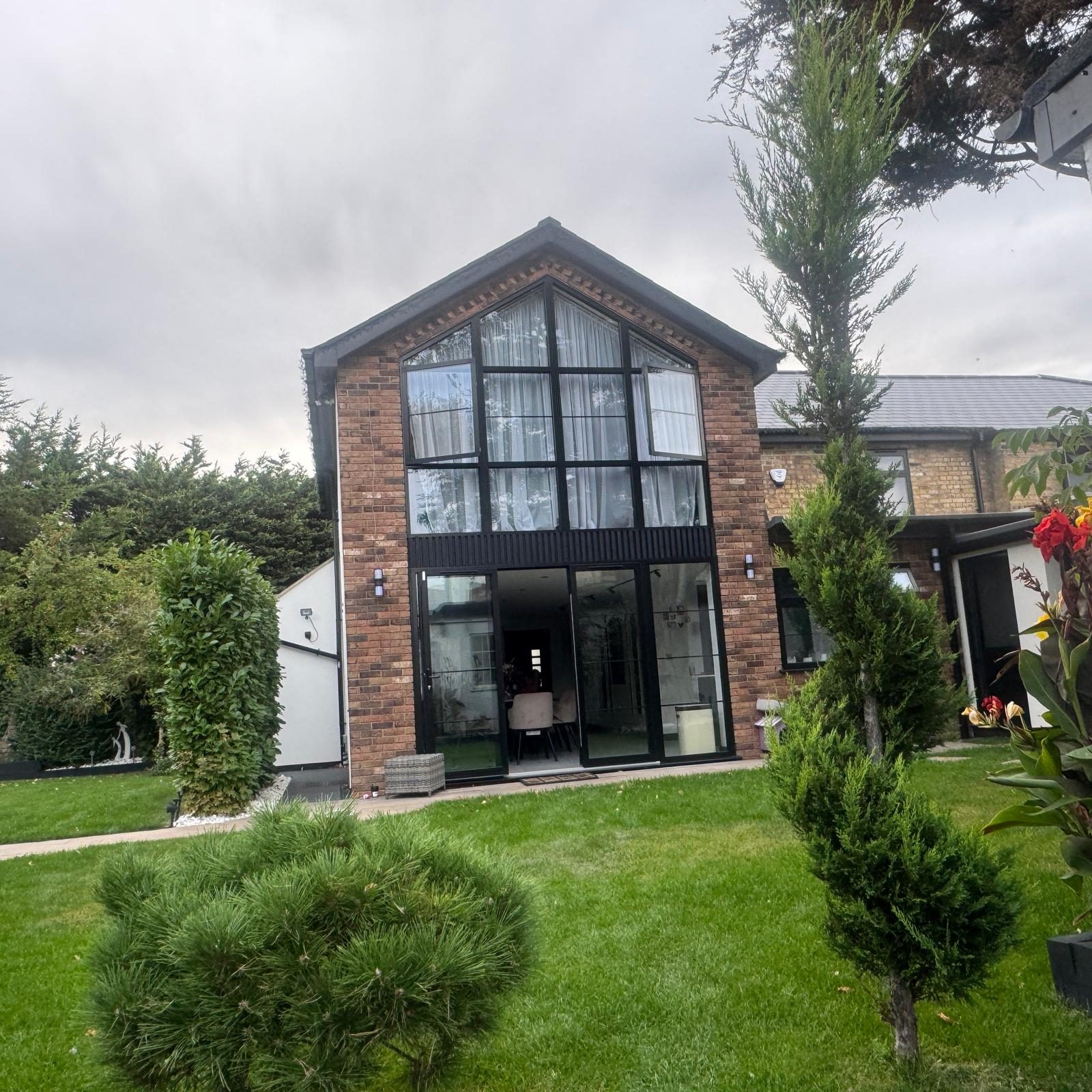 Brick gable extension with full-height glazing and sliding doors opening onto a new lawn