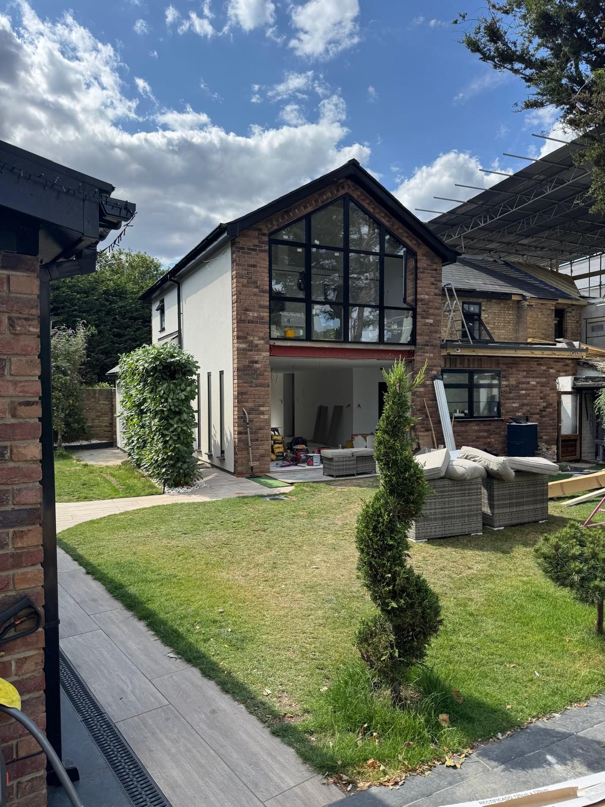 Side view of a glazed brick gable extension with rendered walls, lawn and topiary