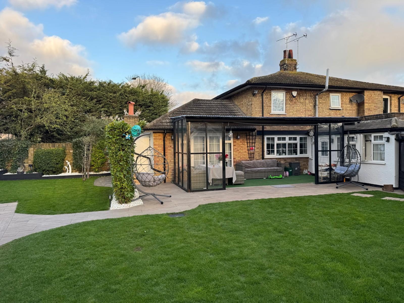 Glazed garden room across the back of a brick semi-detached house with a new lawn