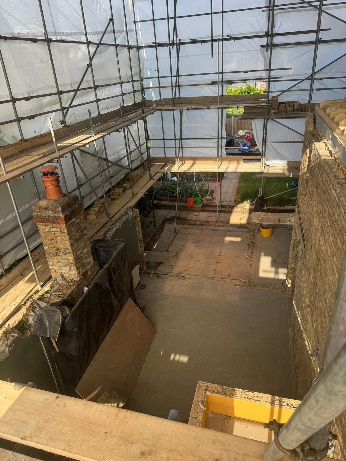 Interior of a house stripped back to bare brickwork and chimney breast under scaffold