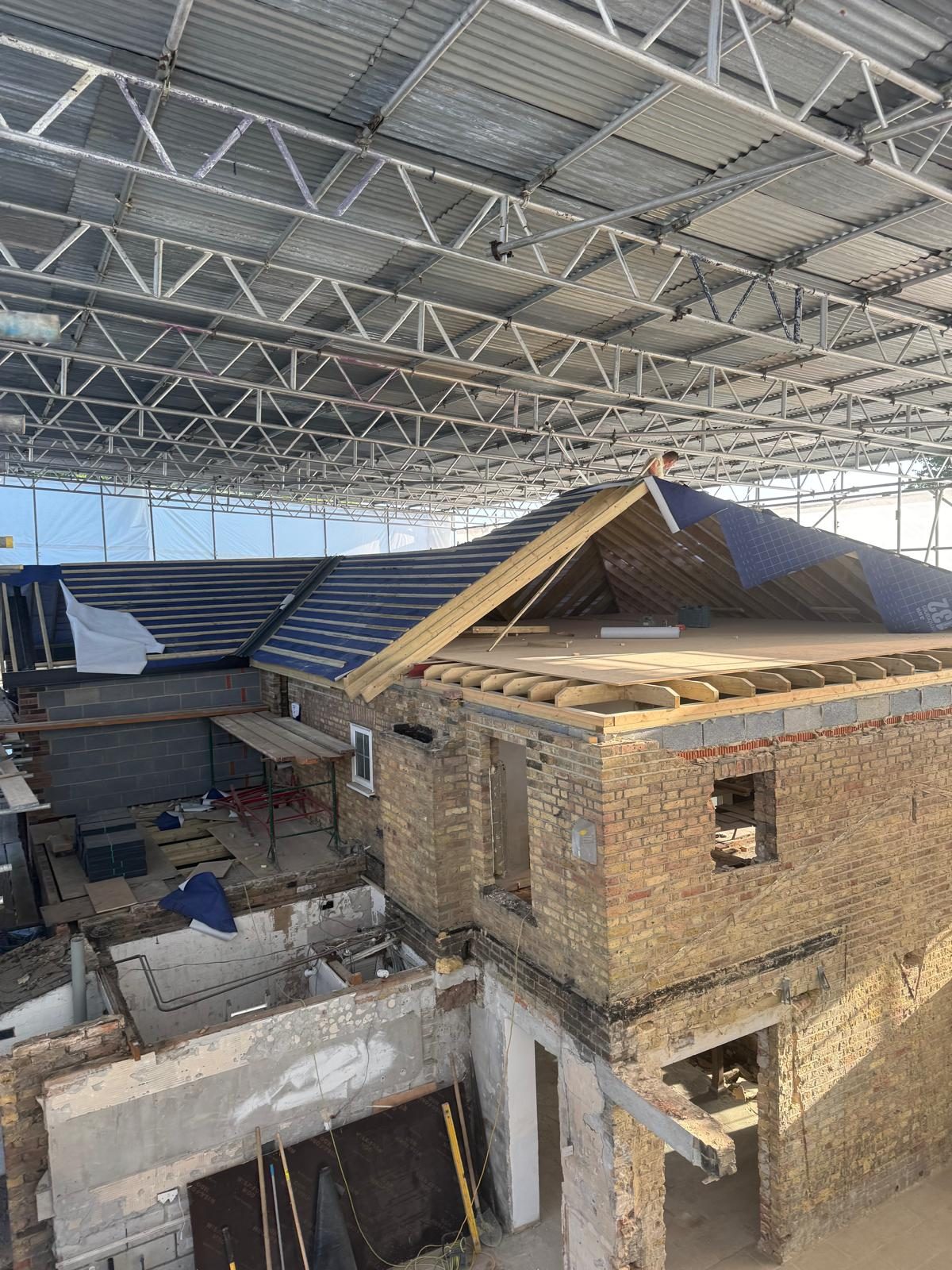 New timber roof structure going onto a brick house under a temporary scaffold roof