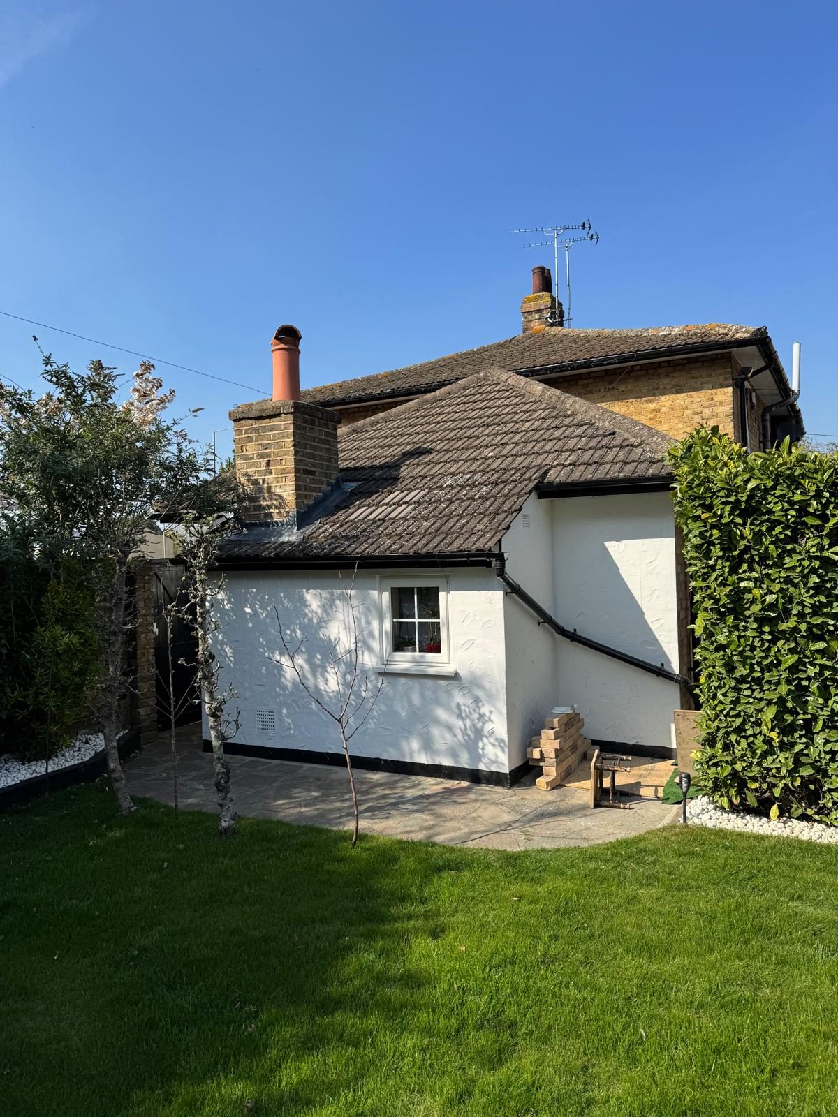 White rendered side elevation with a tiled roof and new lawn